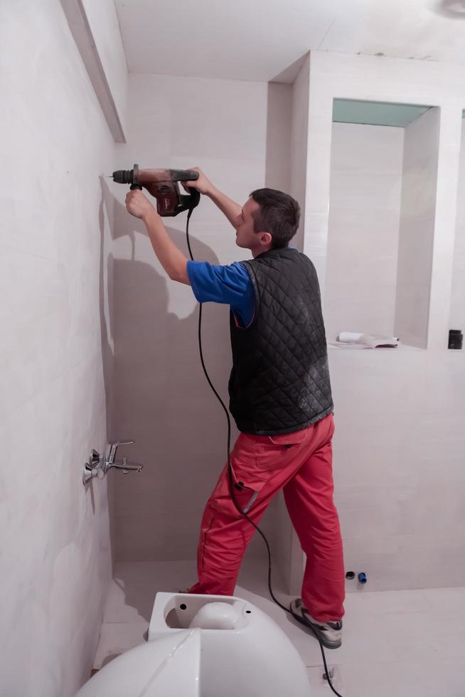 construction worker drilling holes in the bathroom photo