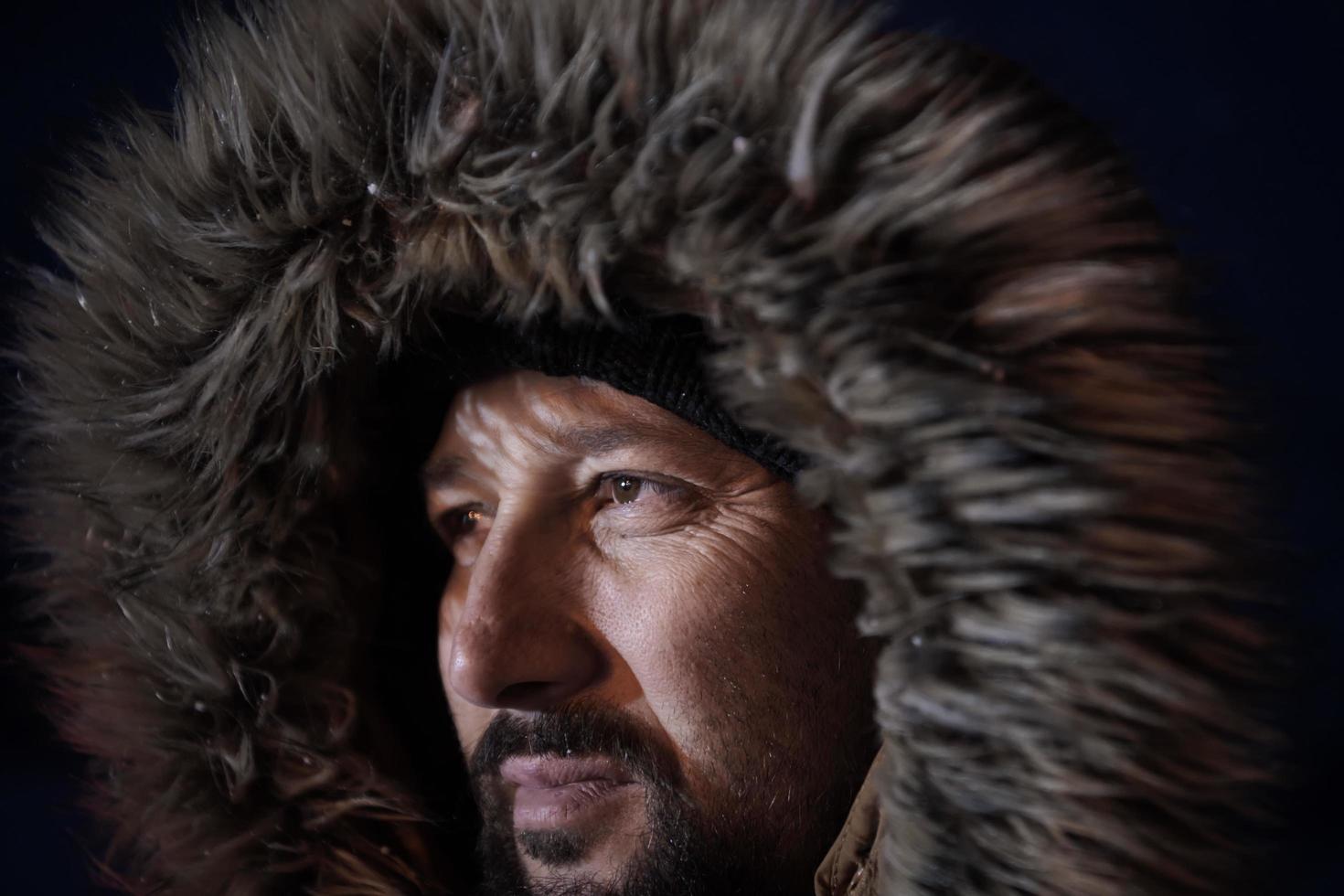 hombre en invierno en una noche tormentosa con una cálida chaqueta de piel foto