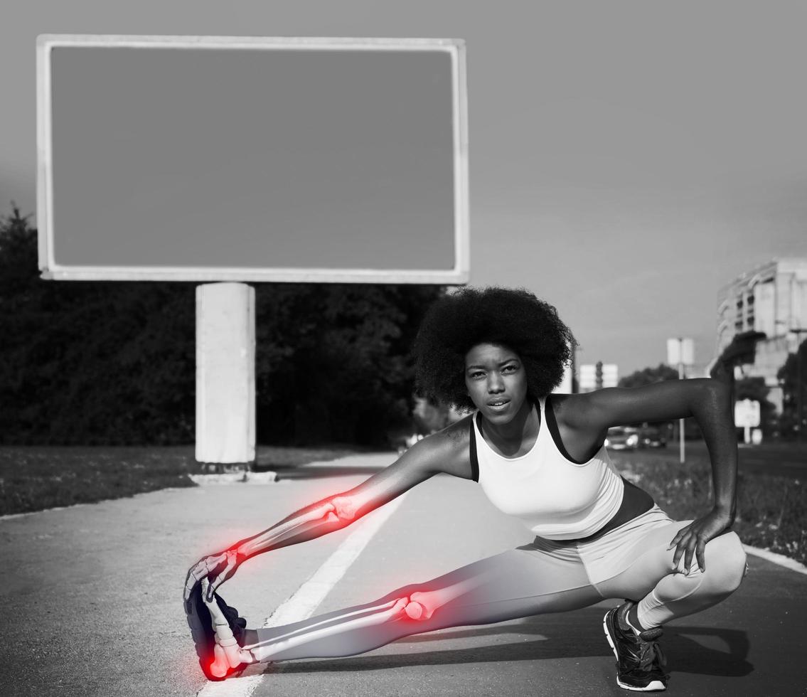 Portrait of sporty young african american woman stretching outdoors with skelethon photo