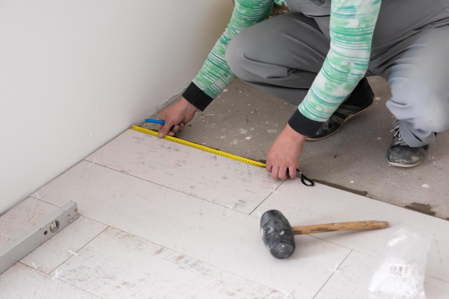 trabajador instalando las baldosas cerámicas con efecto madera en el suelo foto