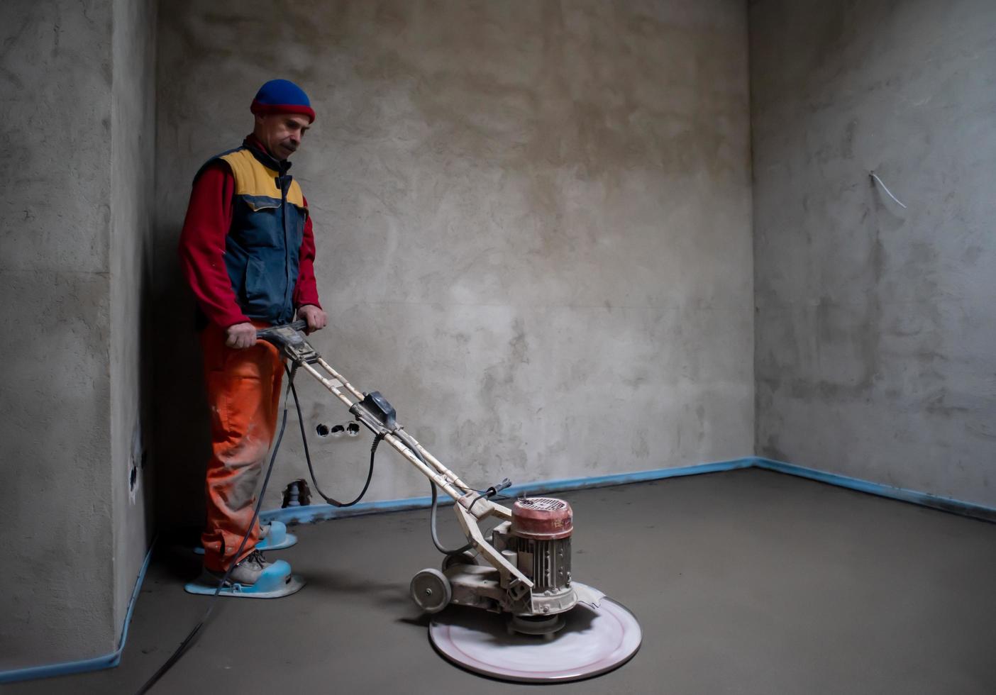 worker performing and polishing sand and cement screed floor photo