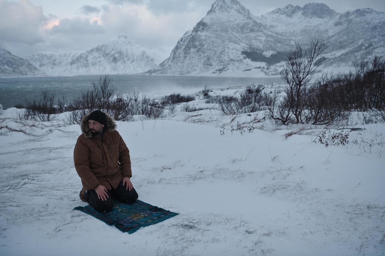 viajero musulmán rezando en el frío día de invierno nevado foto