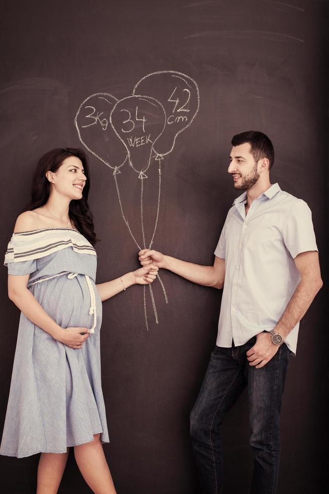 pregnant couple drawing their imaginations on chalk board photo