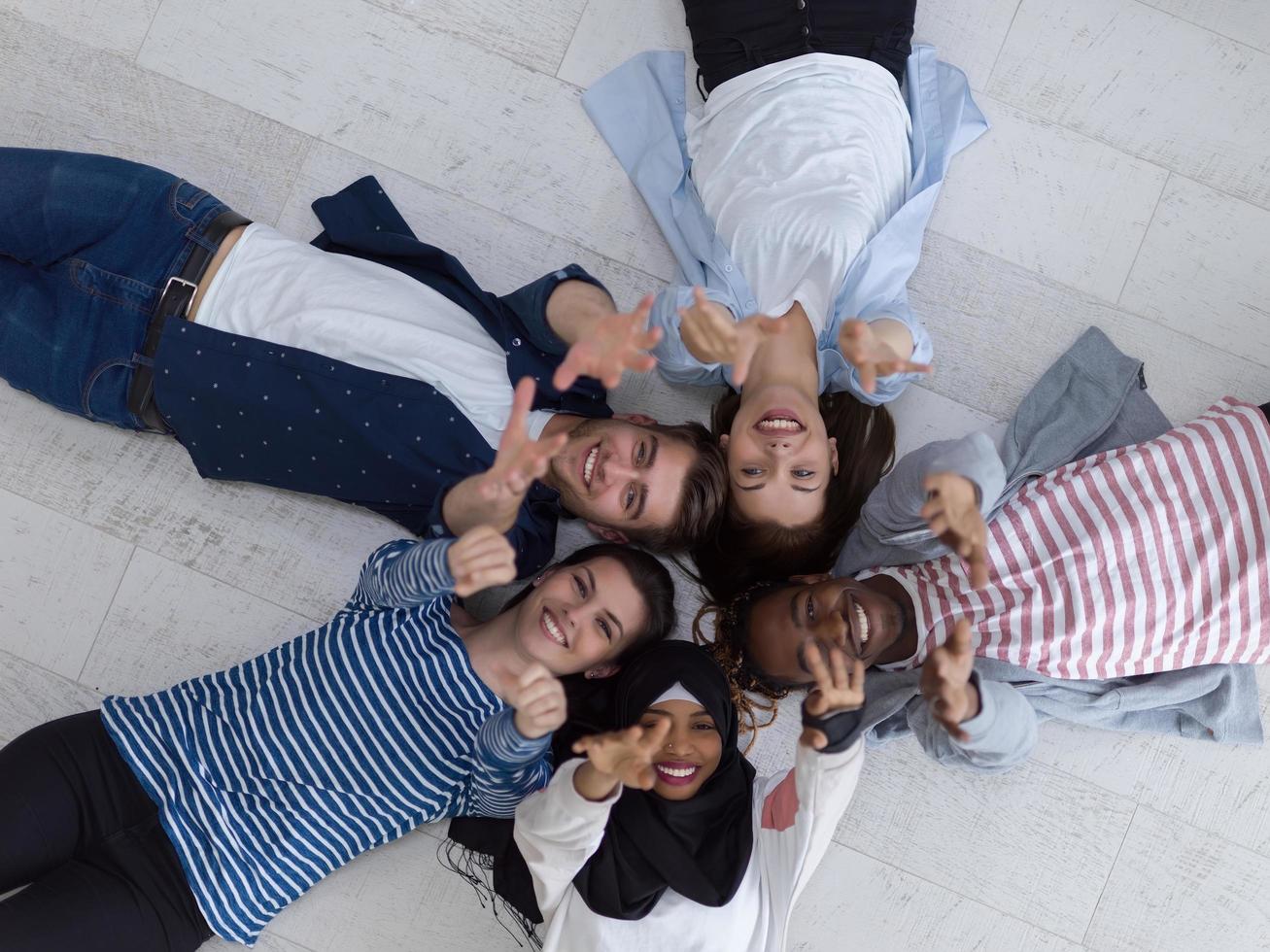 vista superior de un grupo diverso de personas tiradas en el suelo y simbolizando la unión foto