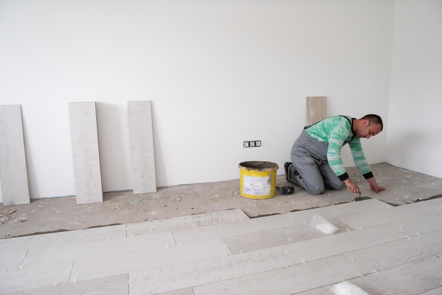 worker installing the ceramic wood effect tiles on the floor photo