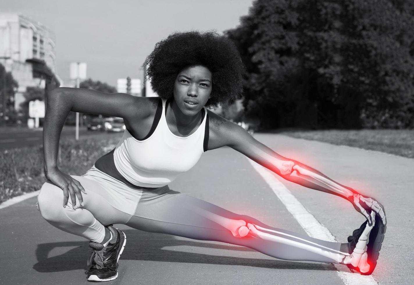 Portrait of sporty young african american woman stretching outdoors with skelethon photo