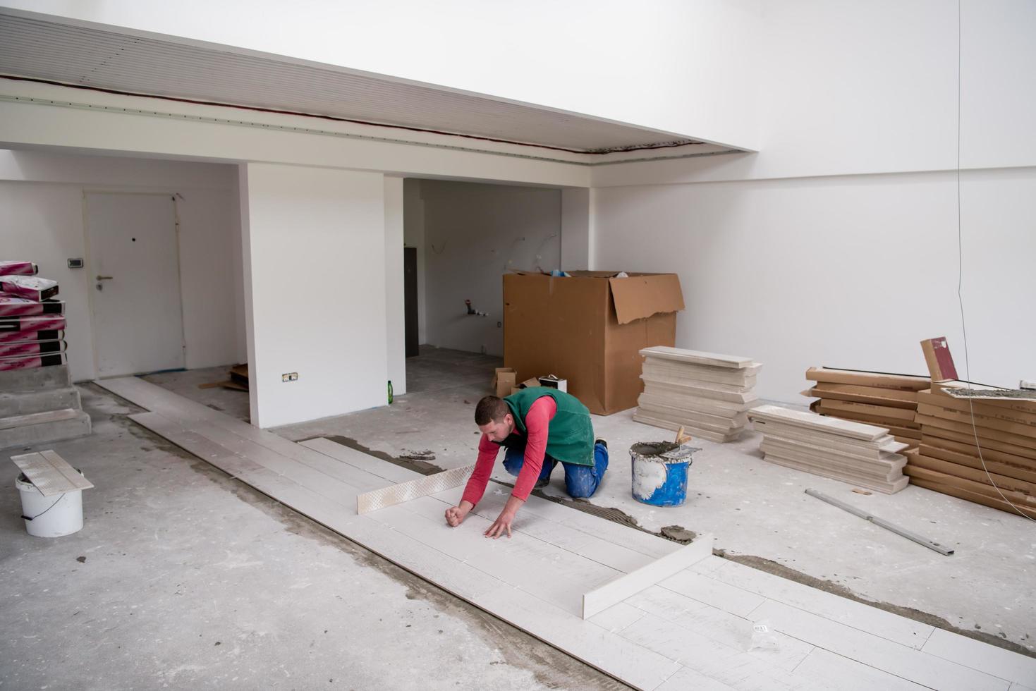 worker installing the ceramic wood effect tiles on the floor photo