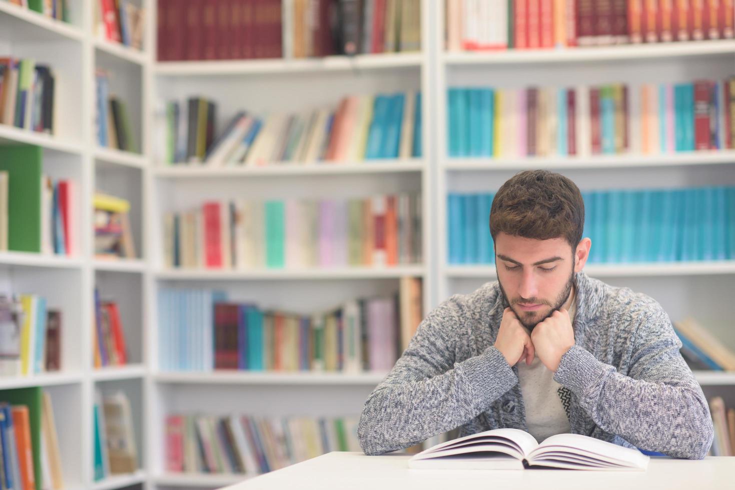 portrait of student while reading book  in school library photo