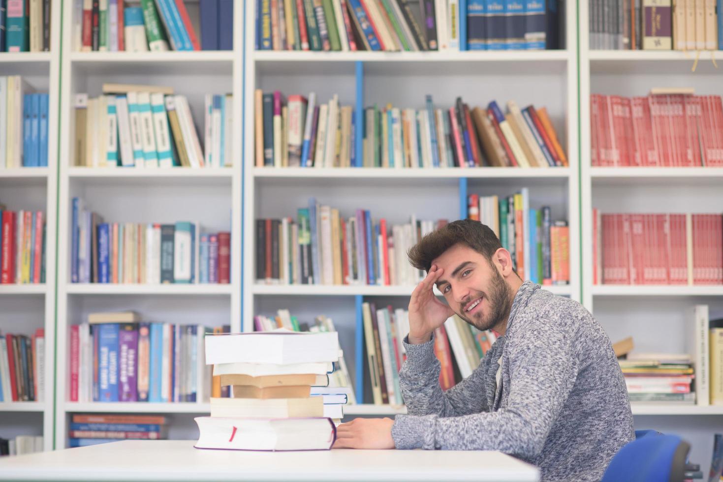 portrait of student while reading book  in school library photo