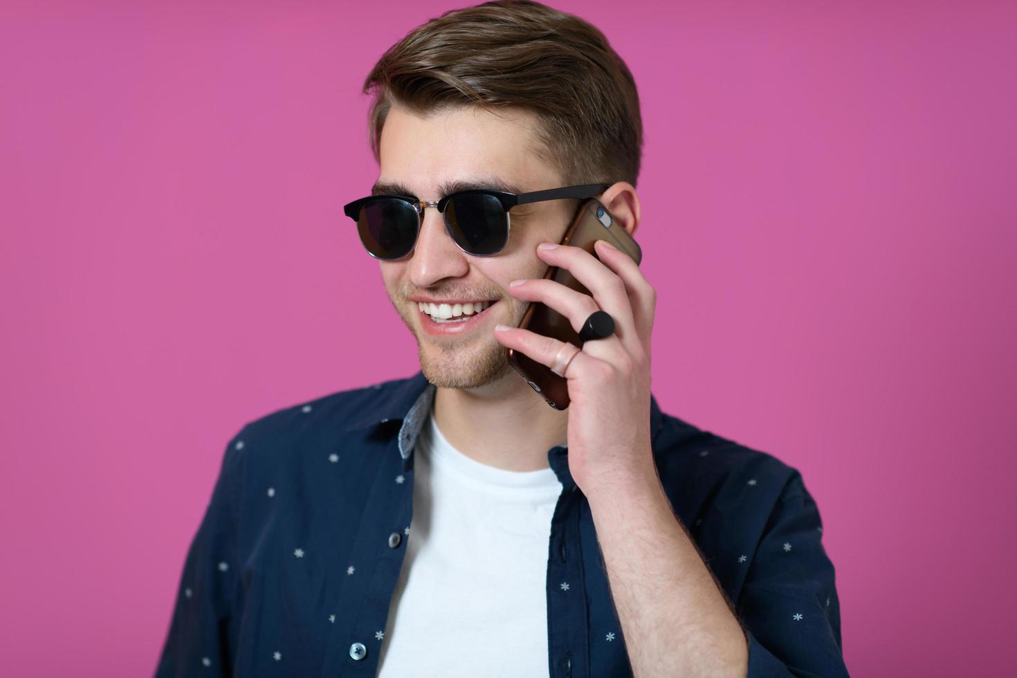 a young man wearing a blue shirt and sunglasses using a smartphone photo