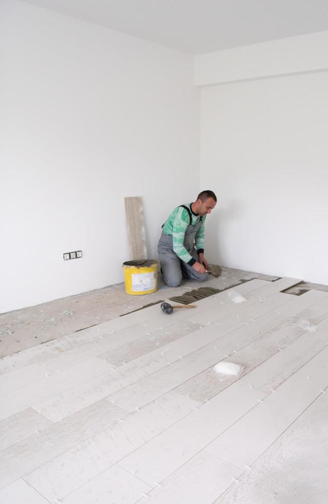 worker installing the ceramic wood effect tiles on the floor photo