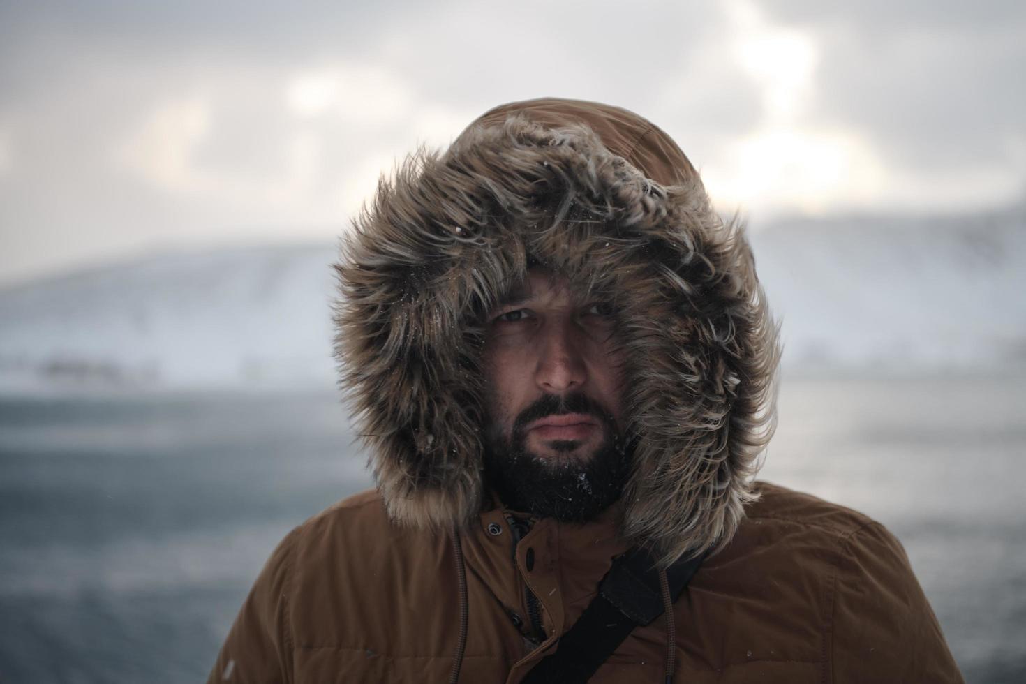 man at winter in stormy weather wearing warm  fur jacket photo