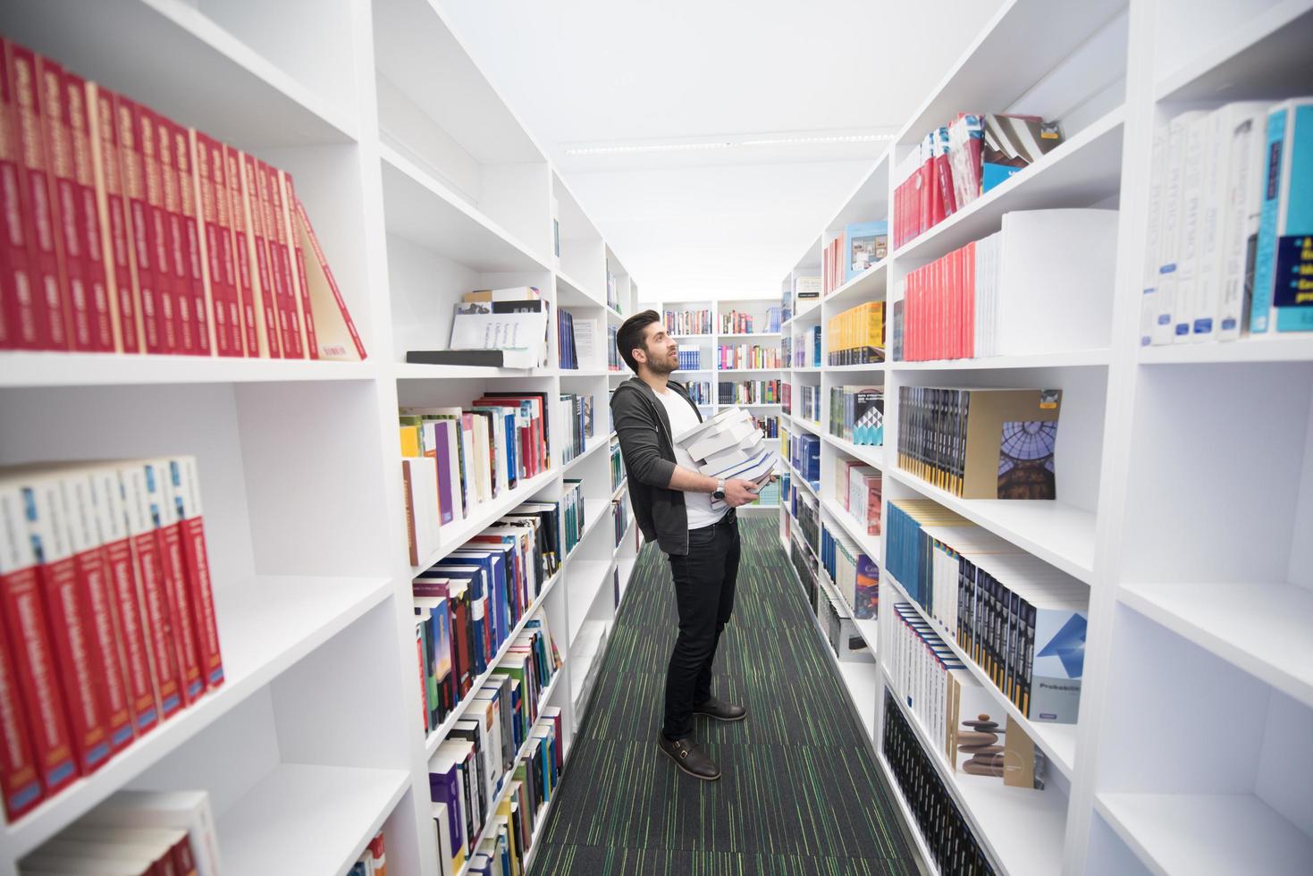 Student holding lot of books in school library photo