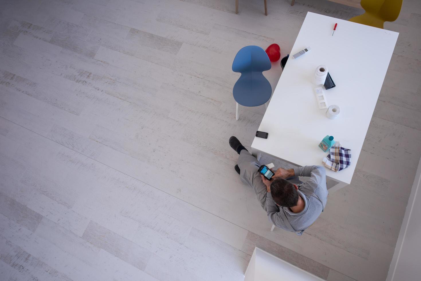 vista superior del joven pintor en traje de trabajo usando teléfono móvil foto