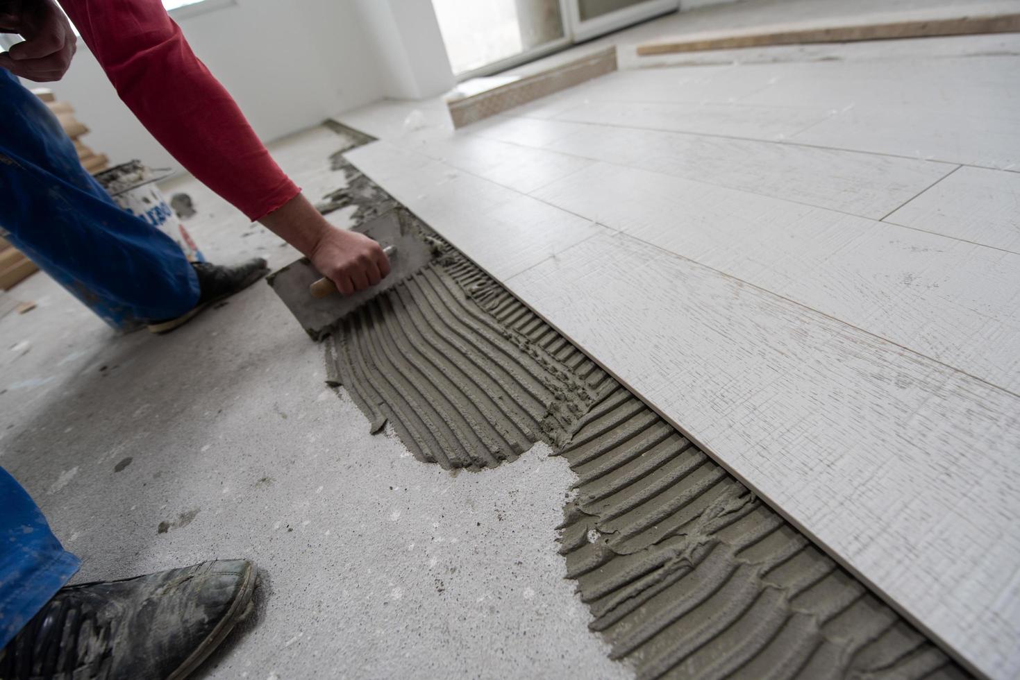 trabajador instalando las baldosas cerámicas con efecto madera en el suelo foto