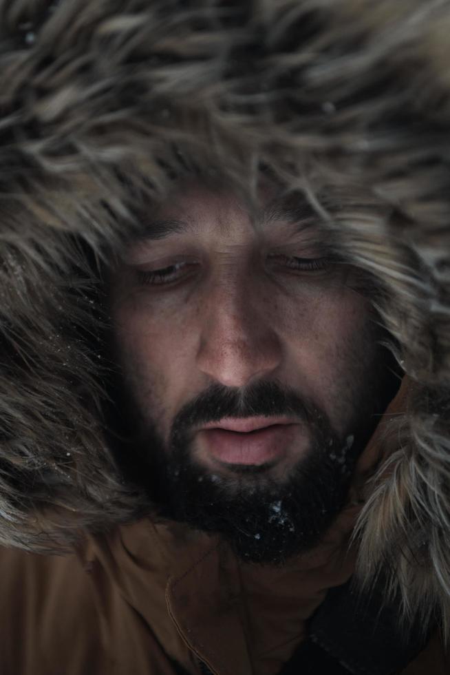 man at winter in stormy weather wearing warm  fur jacket photo