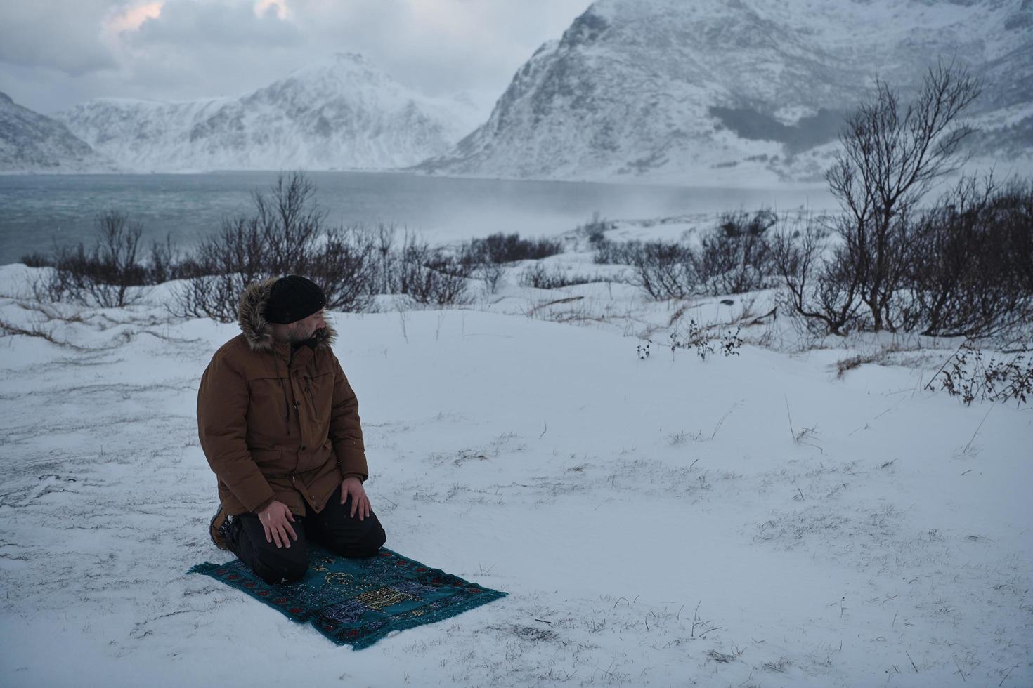 Muslim traveler praying in cold snowy winter day photo