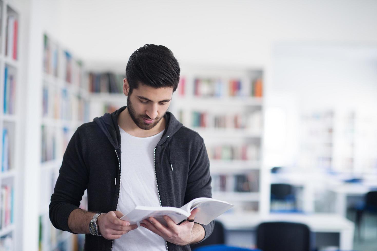 portrait of student while reading book  in school library photo