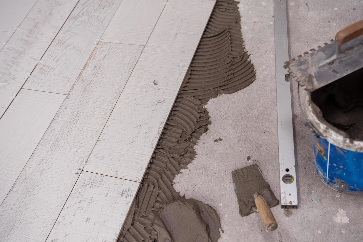 Baldosas cerámicas con efecto de madera y herramientas para baldosas en el suelo. foto