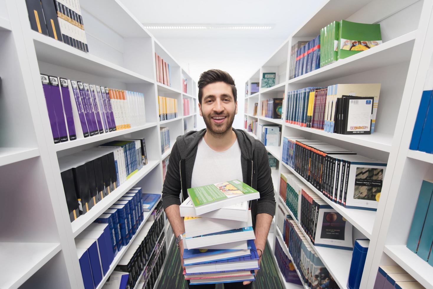 Student holding lot of books in school library photo