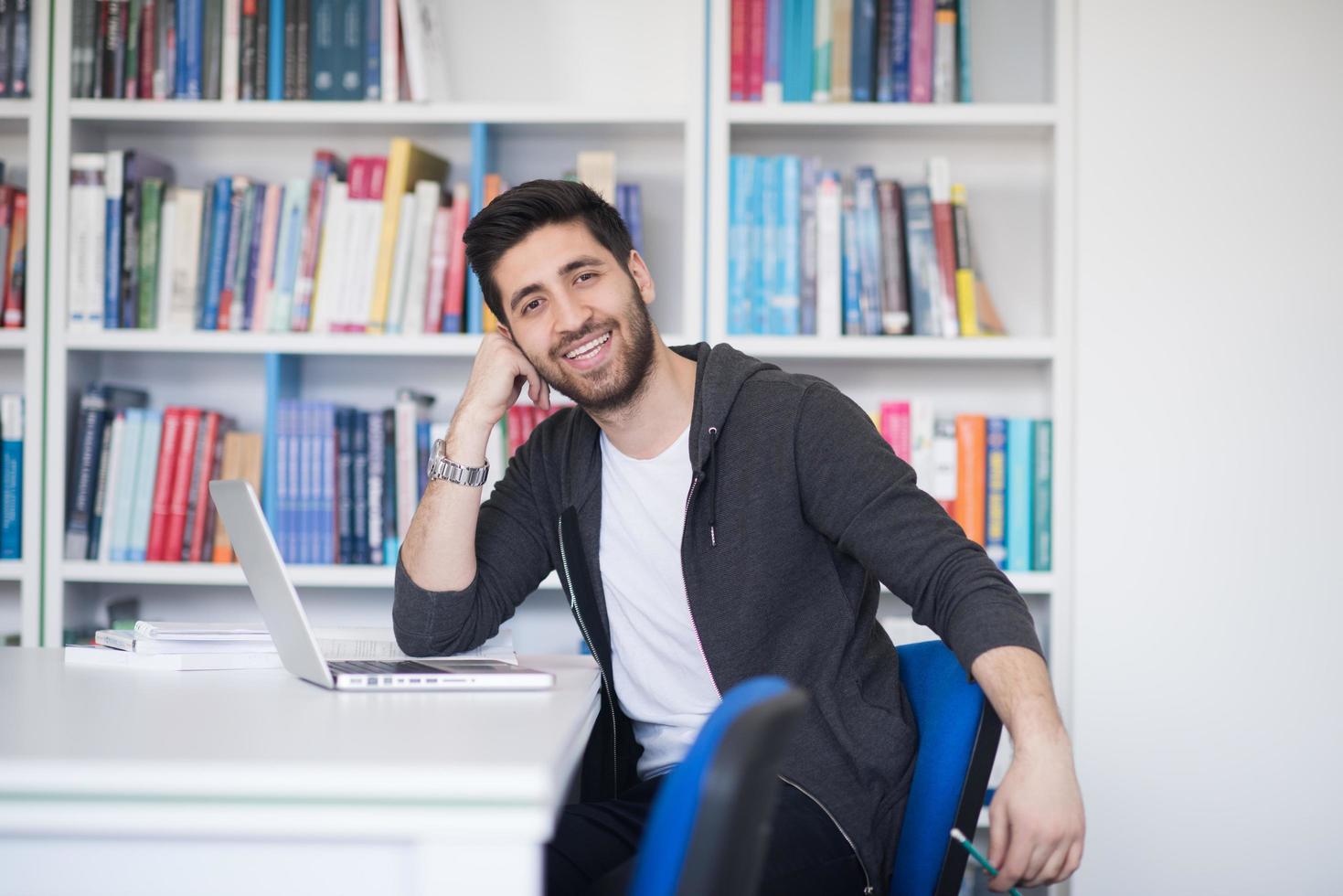 estudiante en la biblioteca escolar usando una computadora portátil para investigar foto