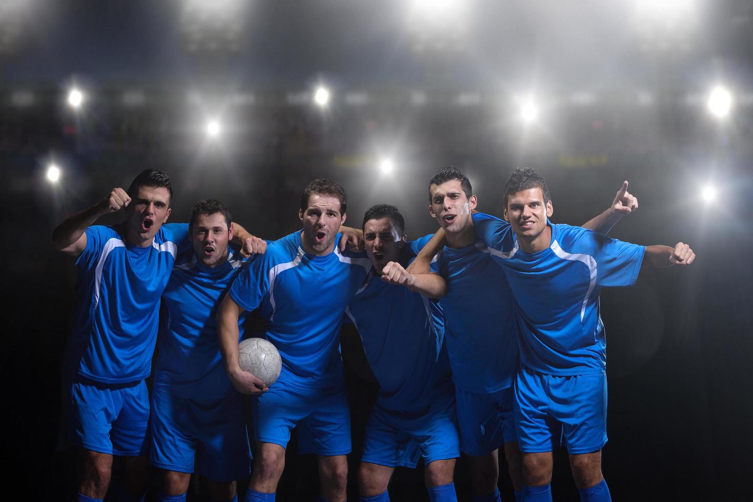 soccer players celebrating victory  in front of big modern stadium with flares and lights photo