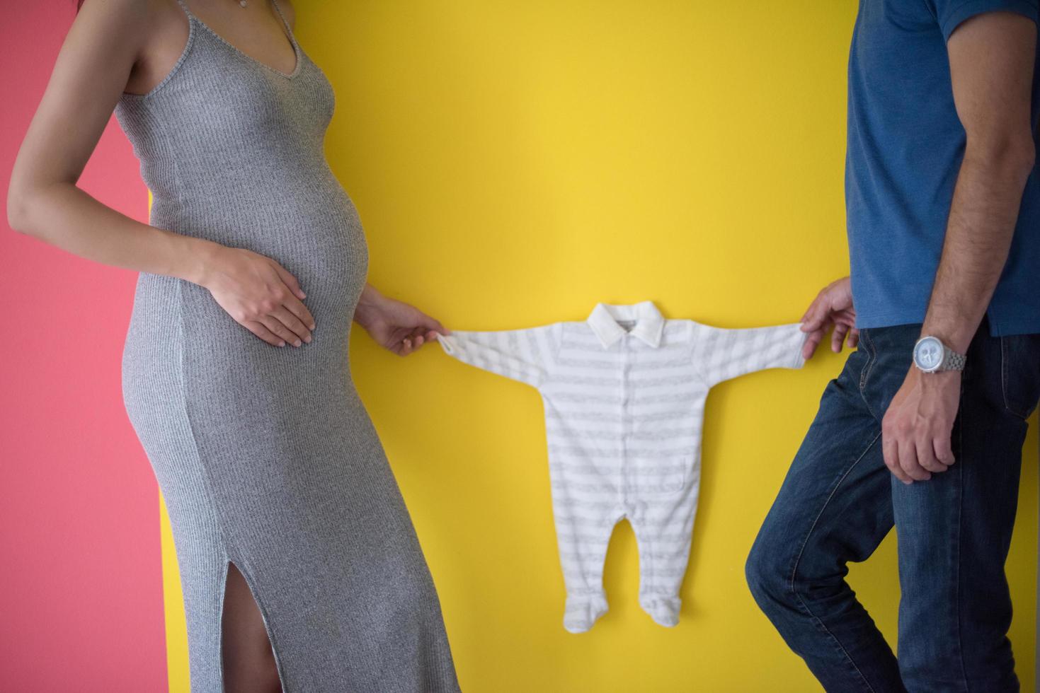 young couple holding baby bodysuits photo