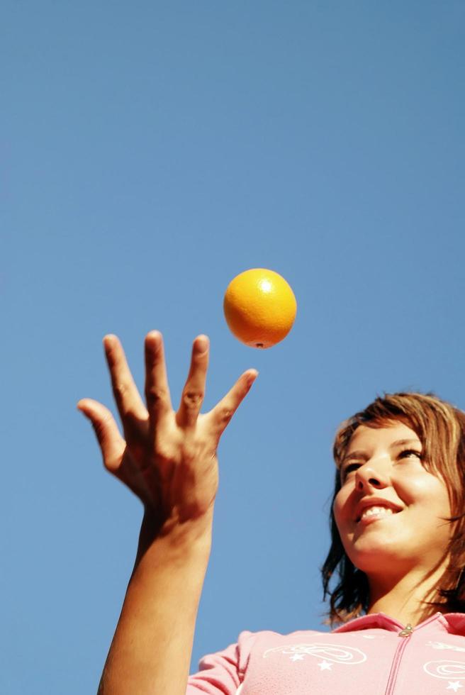 beautyful girl throwing orange in air photo