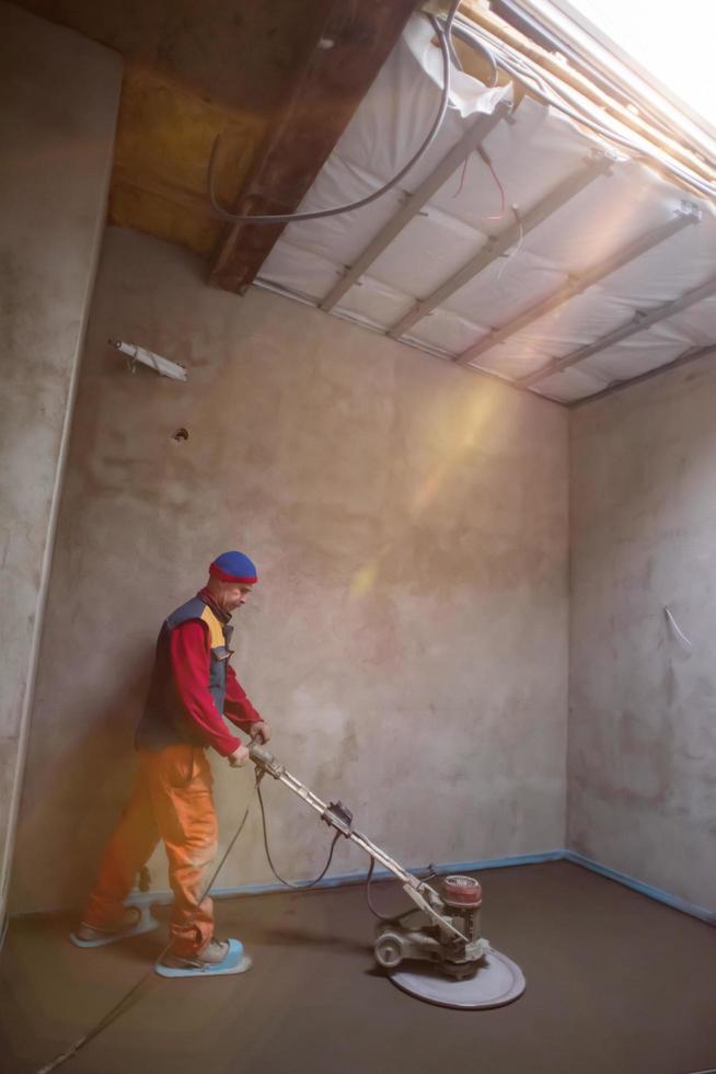 worker performing and polishing sand and cement screed floor photo