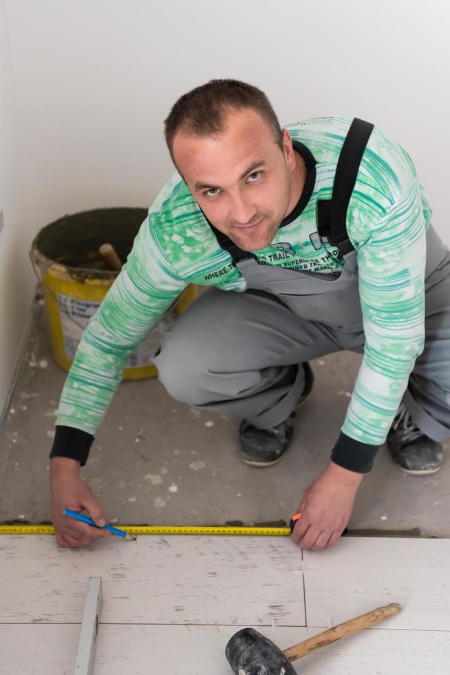 trabajador instalando las baldosas cerámicas con efecto madera en el suelo foto