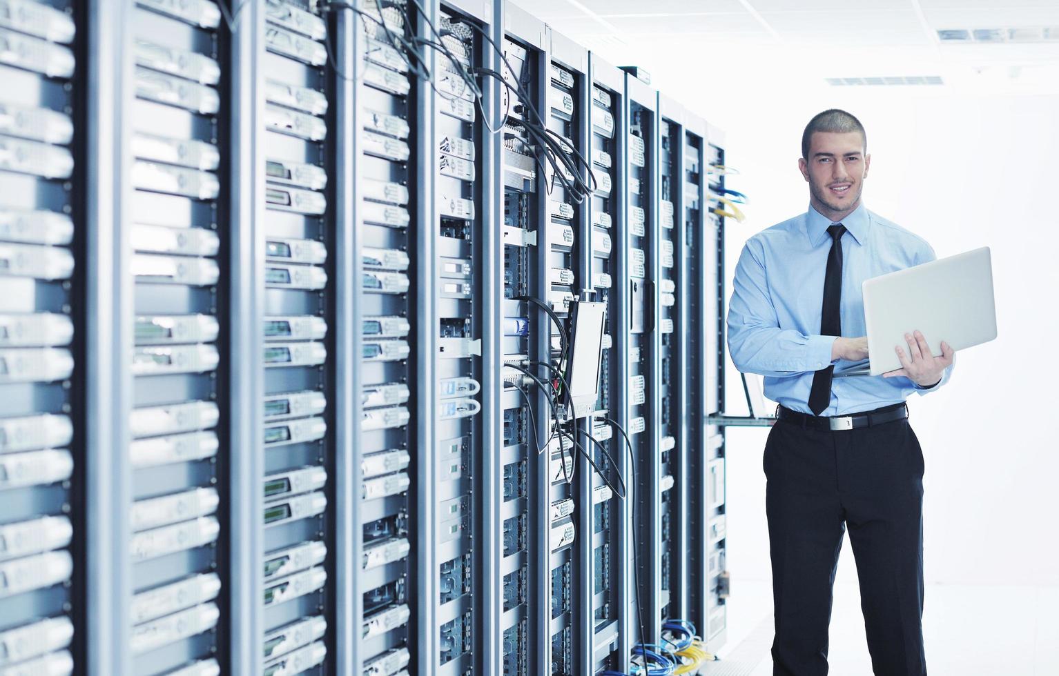 businessman with laptop in network server room photo