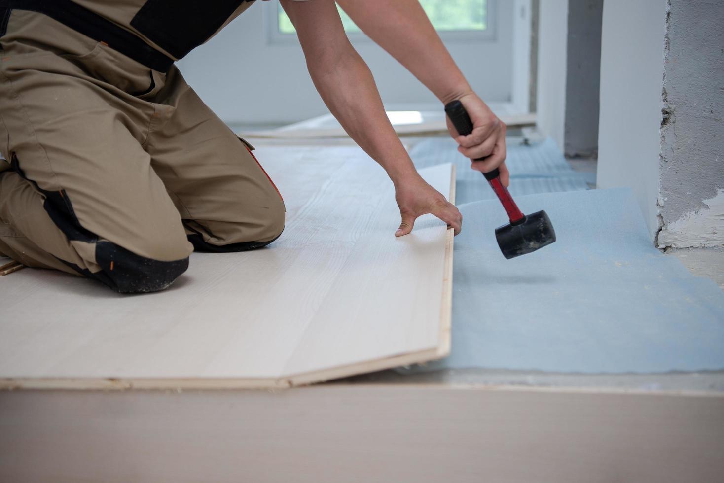 trabajador profesional instalando un nuevo piso de madera laminada foto