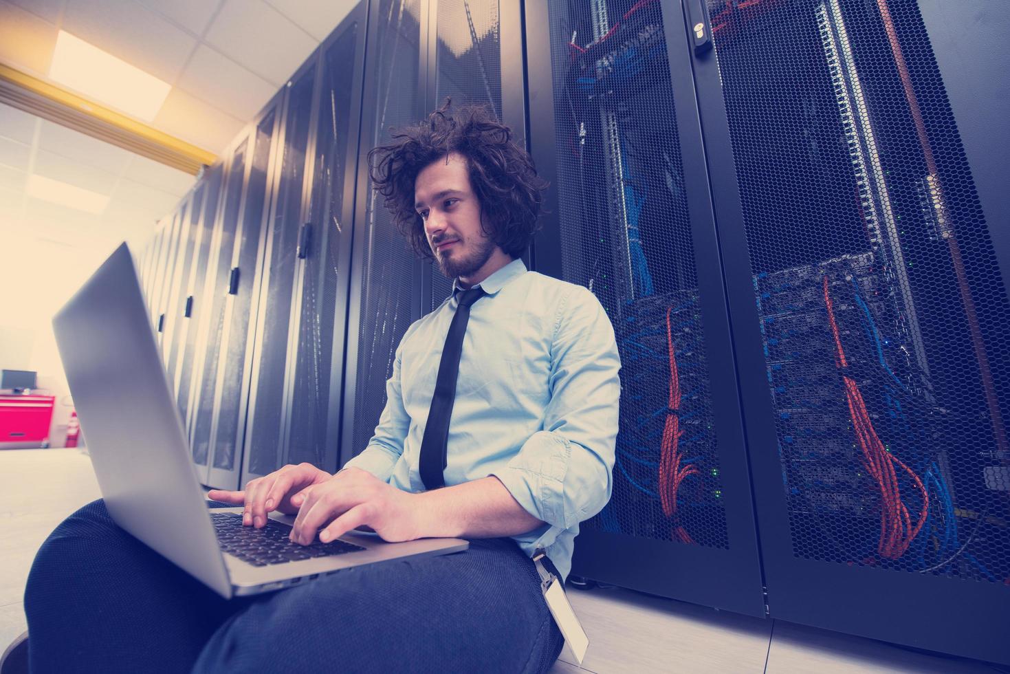 engineer working on a laptop in server room photo