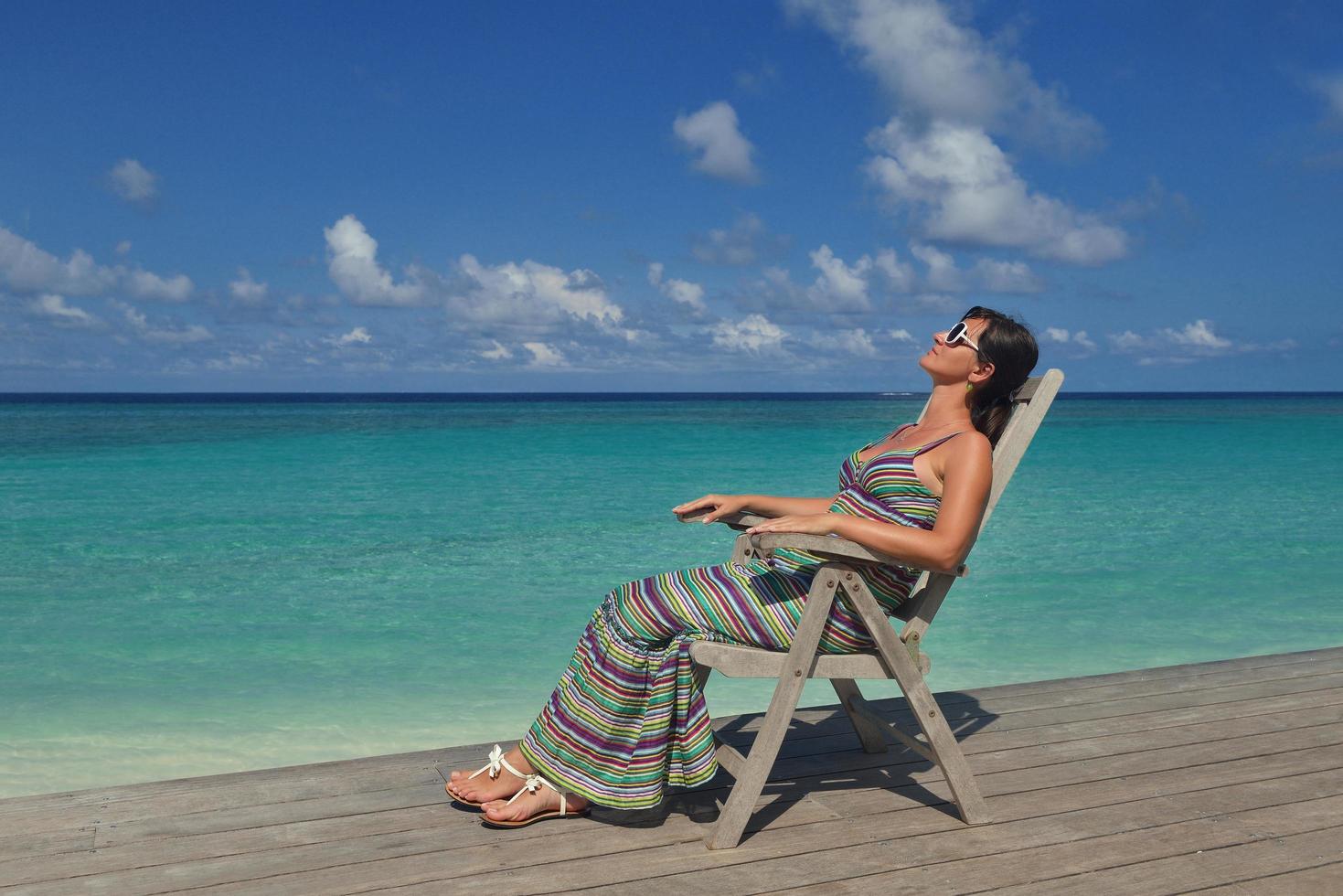 Beautiful young woman with a drink by the sea photo