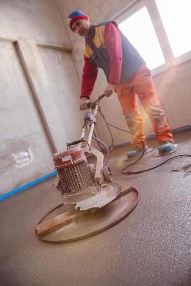 worker performing and polishing sand and cement screed floor photo