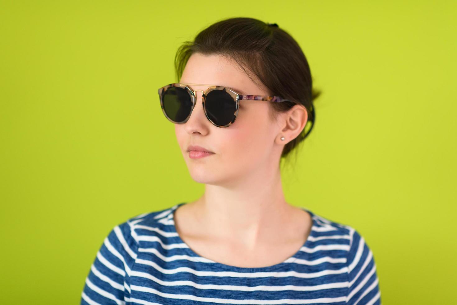 woman  in sunglasses posing in front of a green background photo