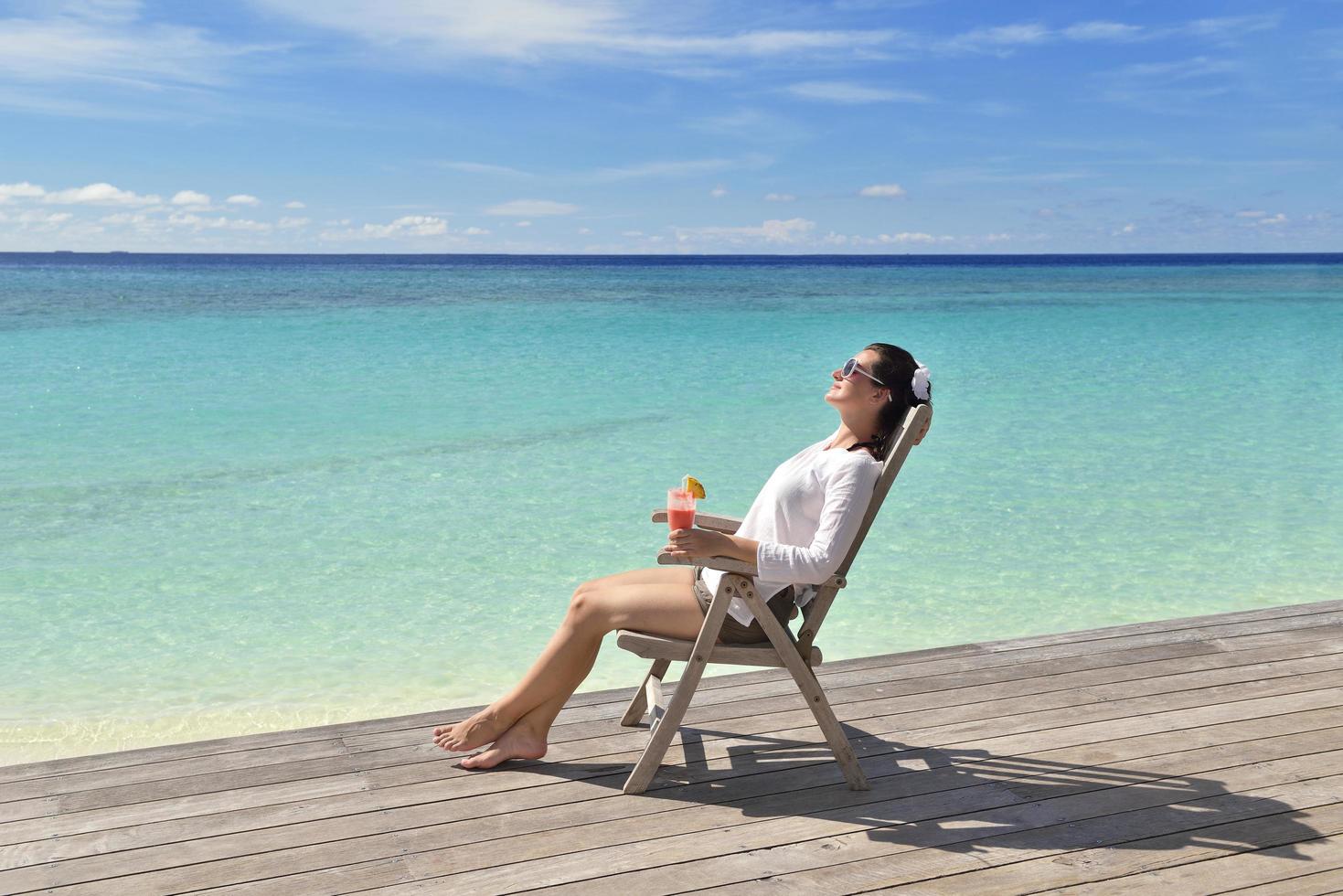 Beautiful young woman with a drink by the sea photo