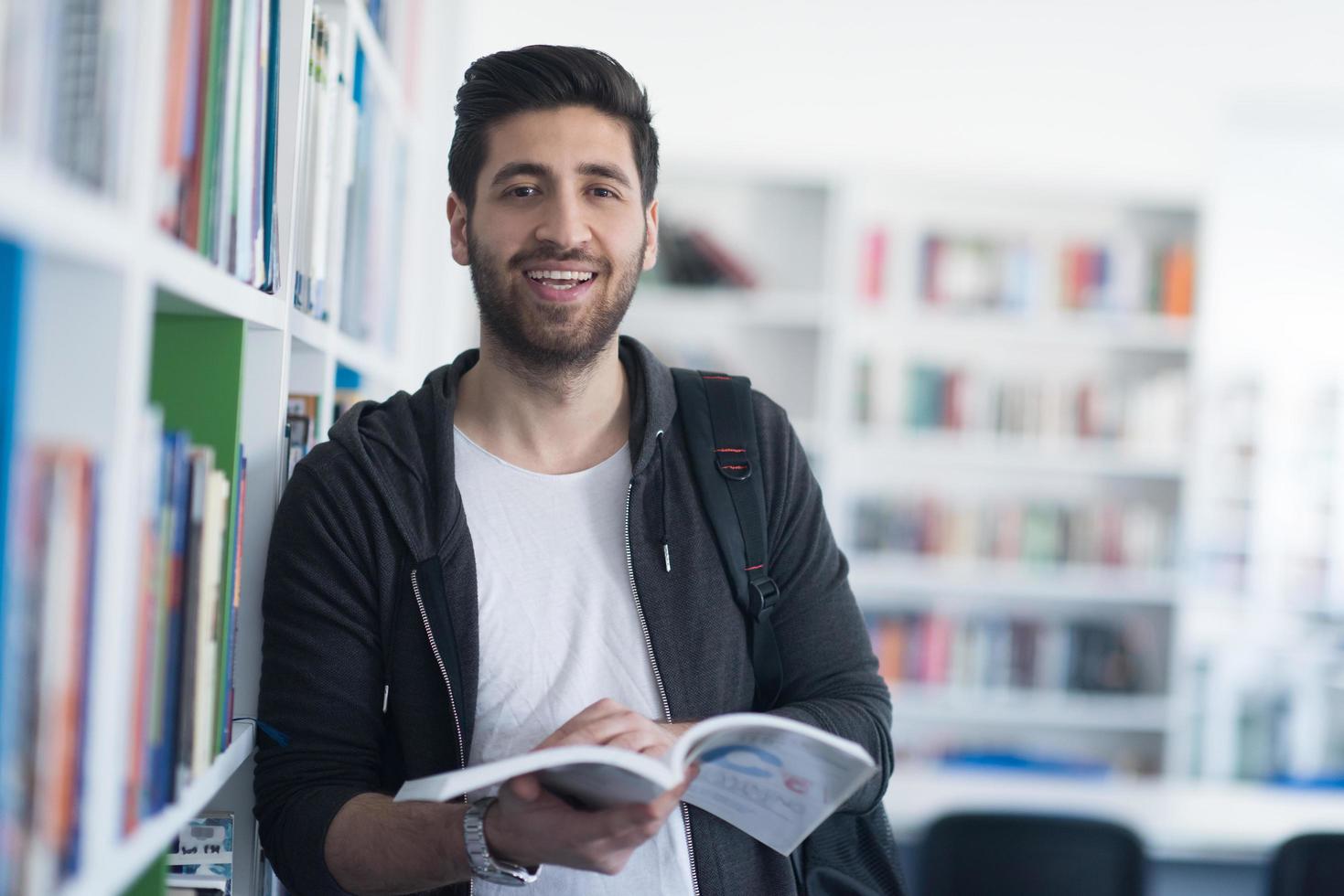 portrait of student while reading book  in school library photo