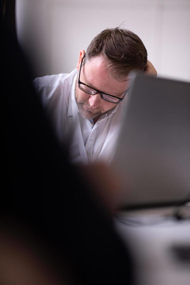Business man writing notes while working on laptop photo