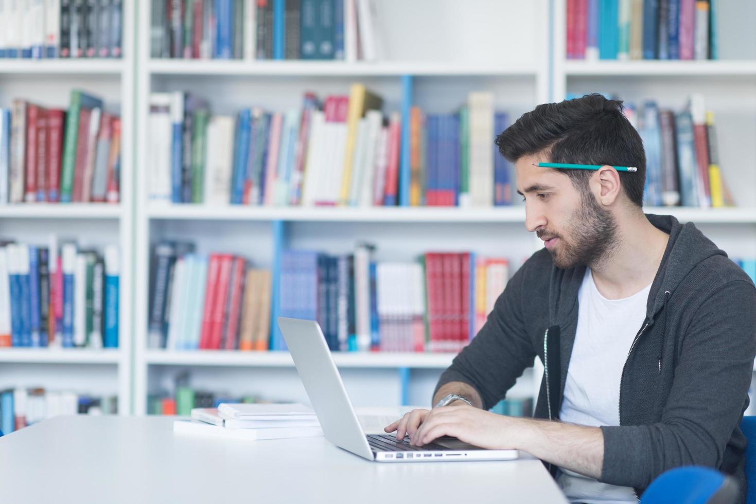 student in school library using laptop for research photo