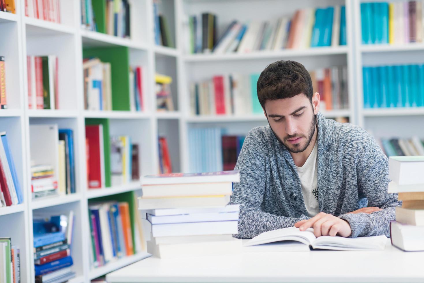 portrait of student while reading book  in school library photo