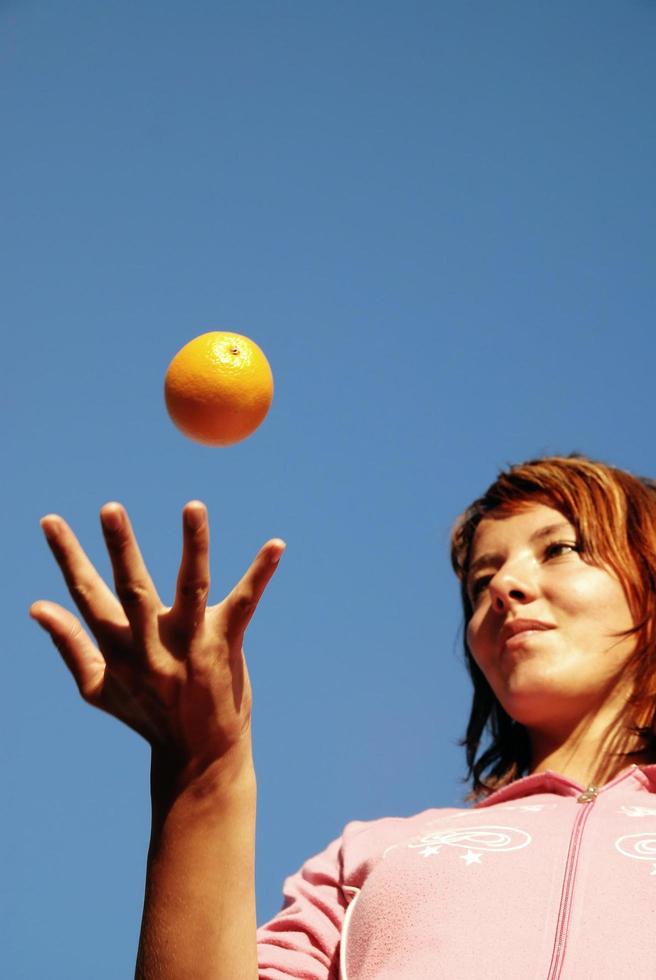 beautyful girl throwing orange in air photo