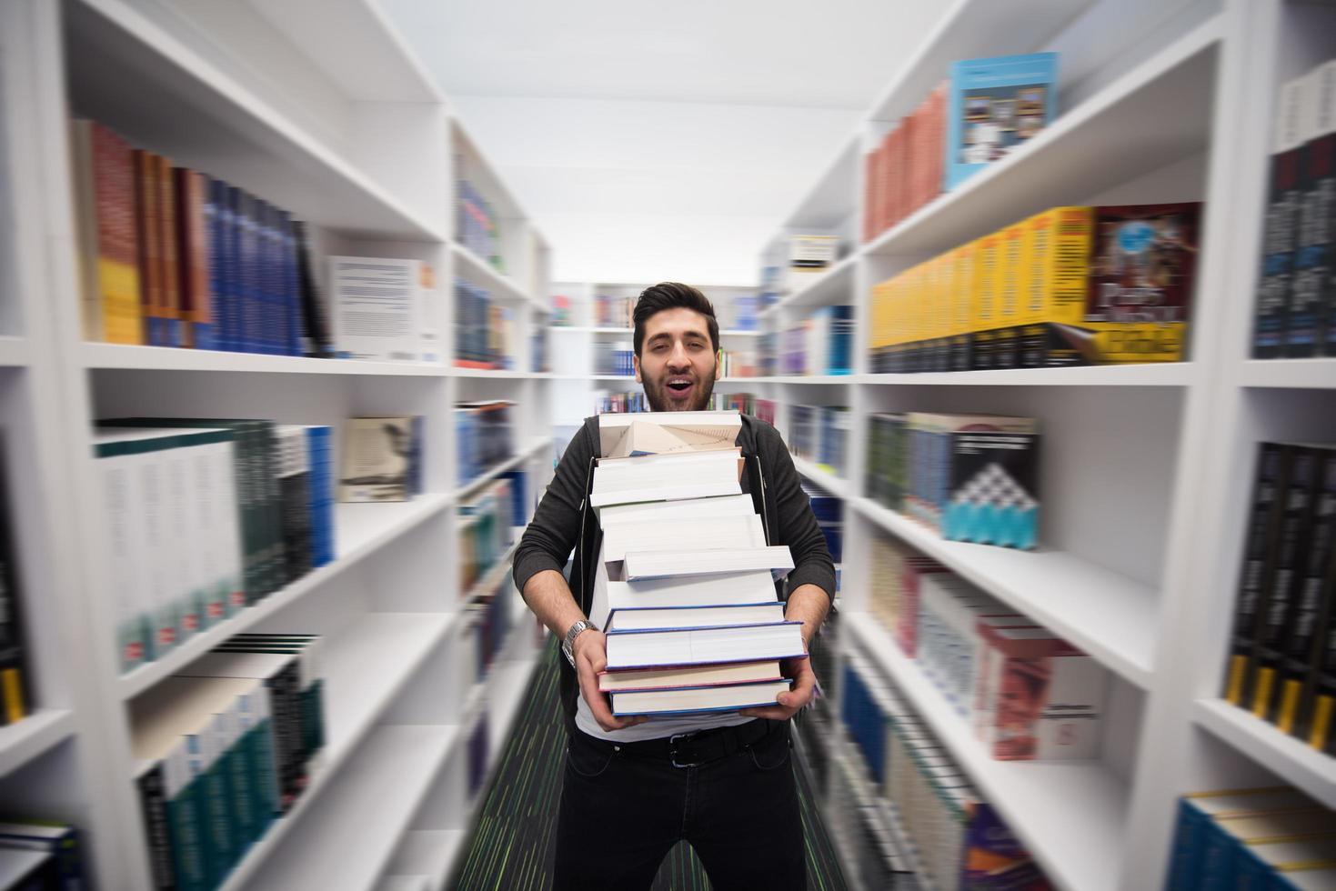 Student holding lot of books in school library photo