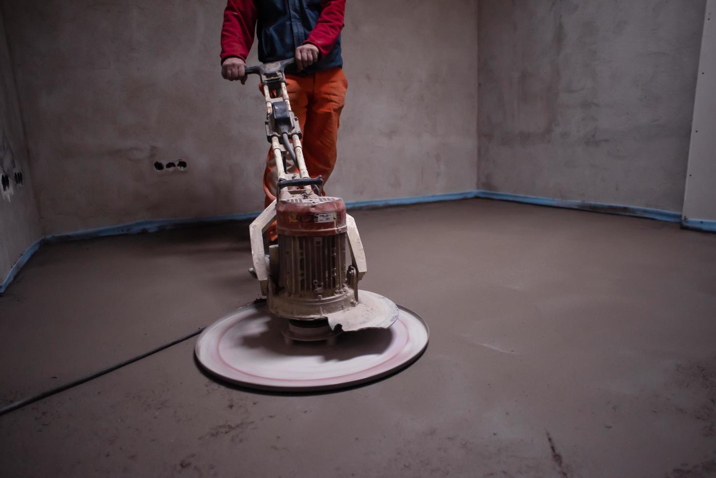 worker performing and polishing sand and cement screed floor photo
