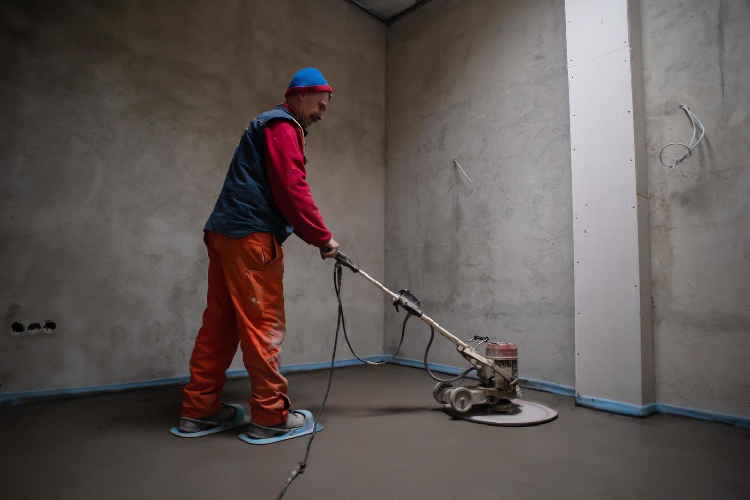 worker performing and polishing sand and cement screed floor photo