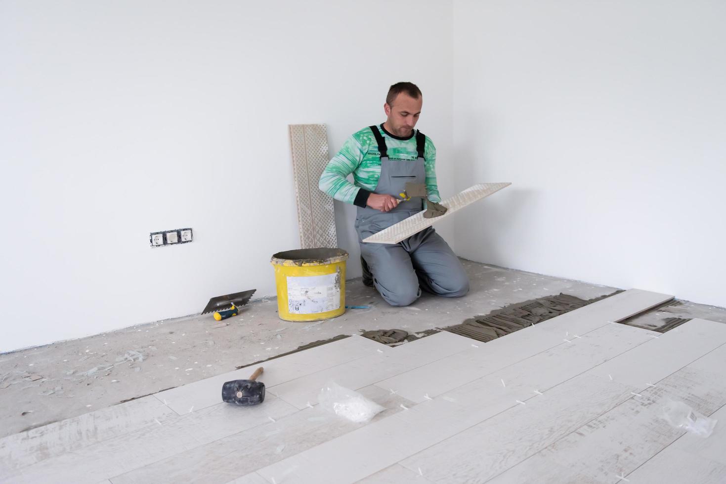 trabajador instalando las baldosas cerámicas con efecto madera en el suelo foto