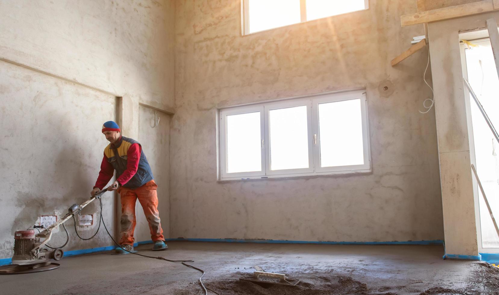 worker performing and polishing sand and cement screed floor photo