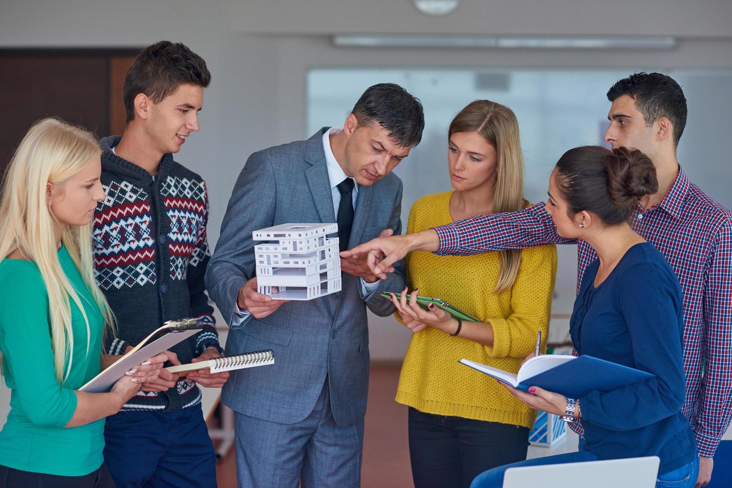 group of students working with teacher on  house model photo