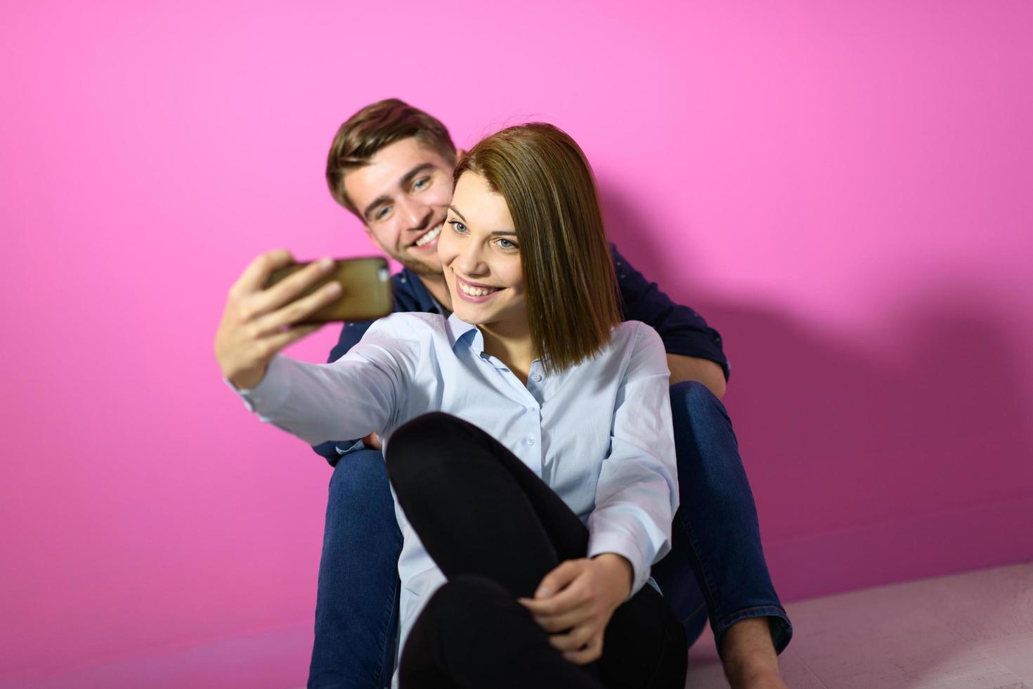 a happy young couple sitting on the floor in the house and making selfie photo