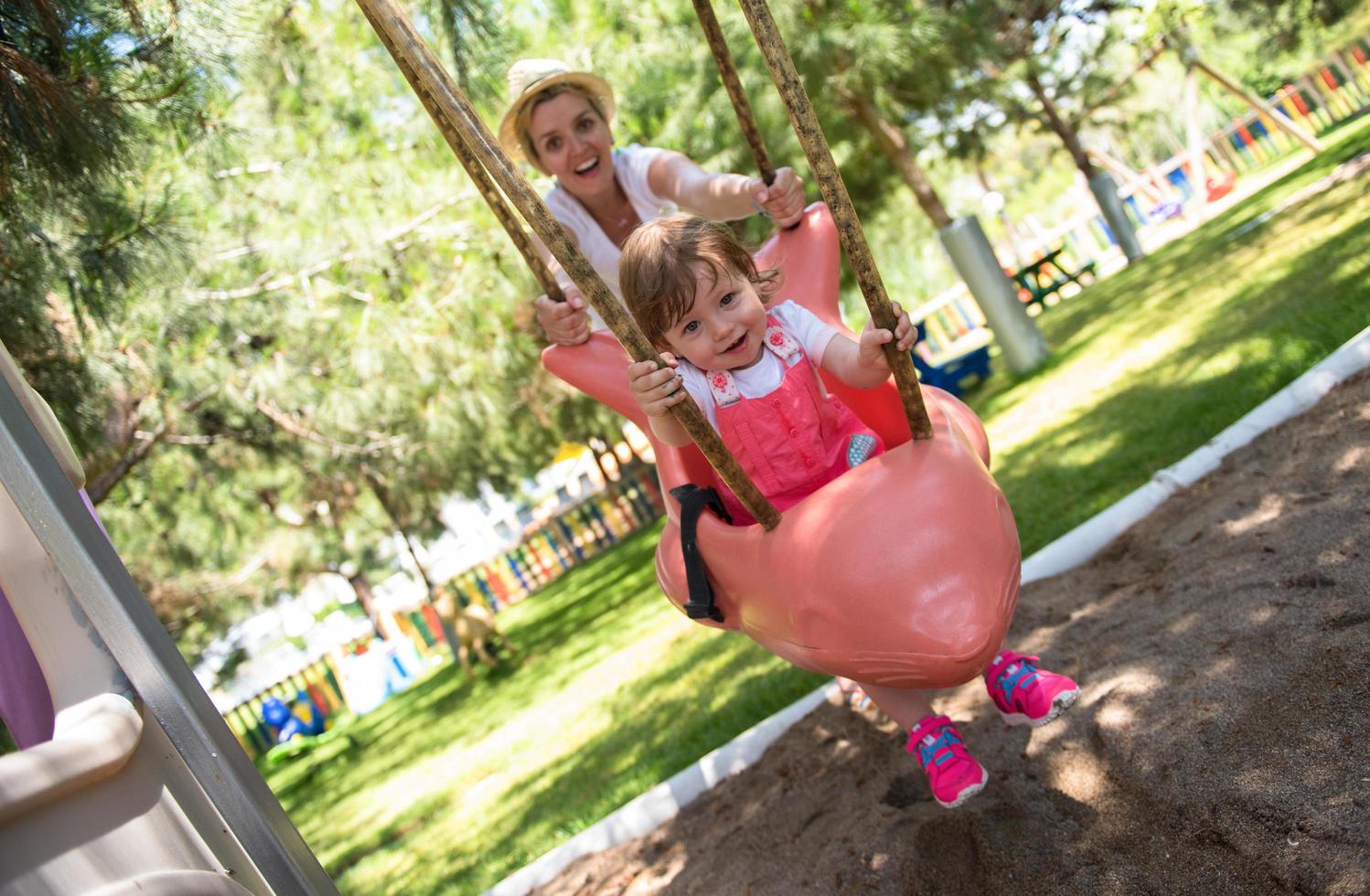 mother and daughter swinging in the park photo